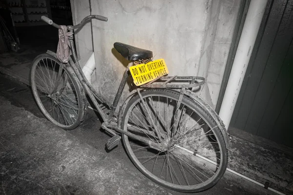 Dirty old pushbike leaning against wall in back street with brig