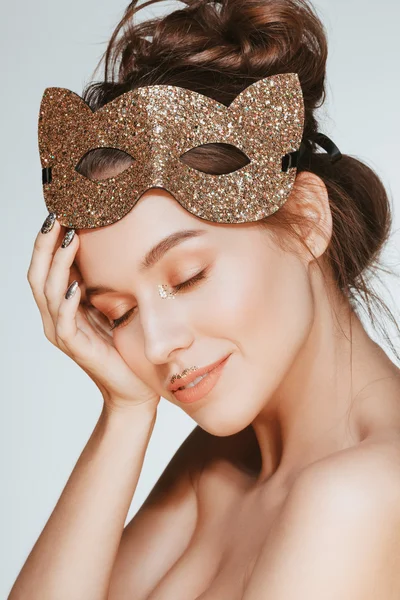 Beautiful attractive happy young brunette model posing in studio with cat mask on her head