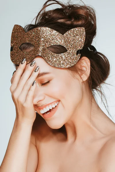 Beautiful attractive happy young brunette model posing in studio with cat mask on her head