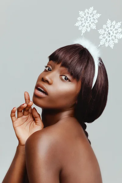 Happy black woman model portrait closeup, facial expression of happiness, with white snowflakes on her head.
