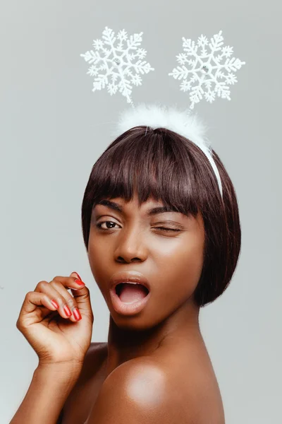 Happy black woman model portrait closeup, facial expression of happiness, with white snowflakes on her head.