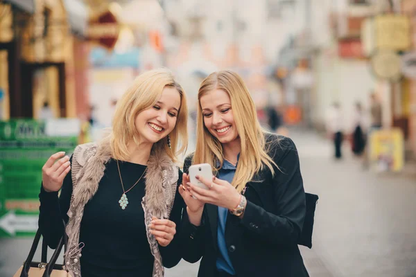 Two pretty girls strolling in the city. The girls are shopping.