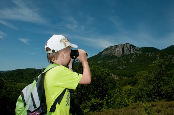 Boy with binoculars looking at the mountain