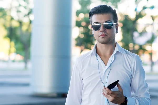 Man with earphones and smartphone walking in city