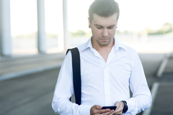 Man using smart phone at station to book airplane tickets