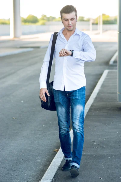 Young stylish man in a hurry looking at his watch