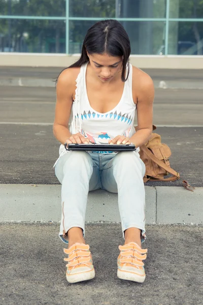 Young pretty woman with tablet sitting at the street