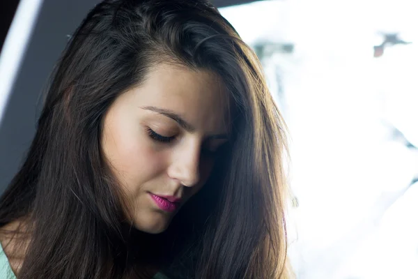 Sad young woman looking down with light on background