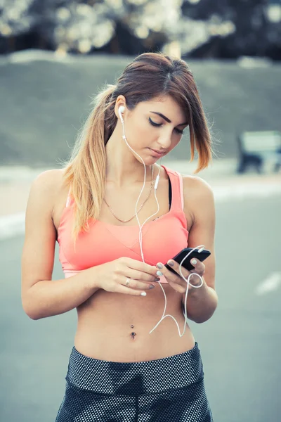 Young female runner turns on the music before the run
