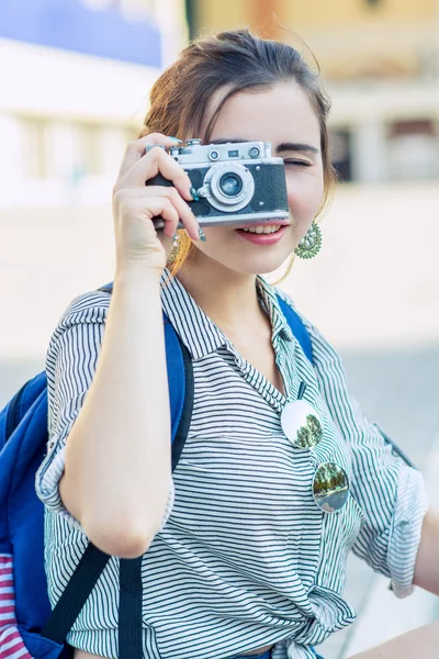 Happy young tourist woman or teenage girl with film camera