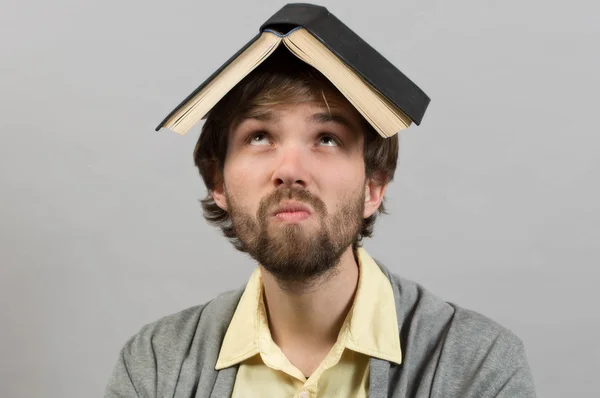 Guy with book on head thinking over grey background