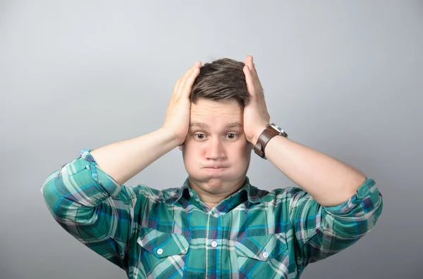 Portrait of frustrated shocked man in shirt standing against grey background