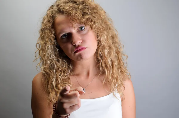 Curly woman point finger at you looking at camera.