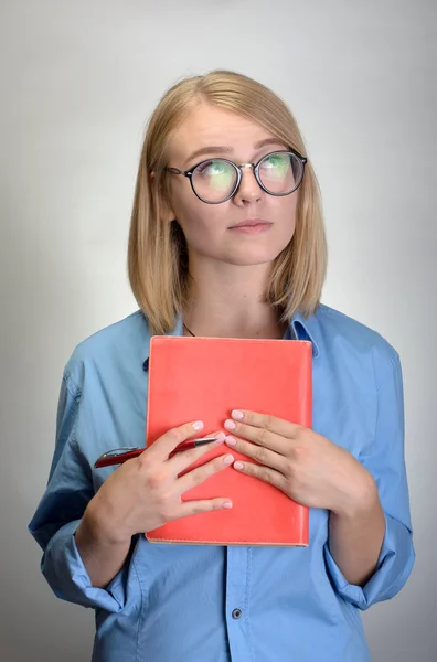 Portrait of young woman with notebook and pen