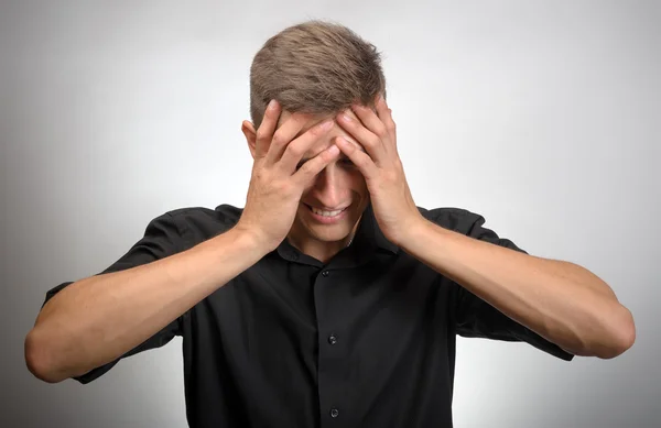 The man really tired, he covered his face with his hands. Gray background