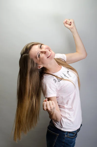 Pretty young excited woman with her hands under chin, isolated against grey  background