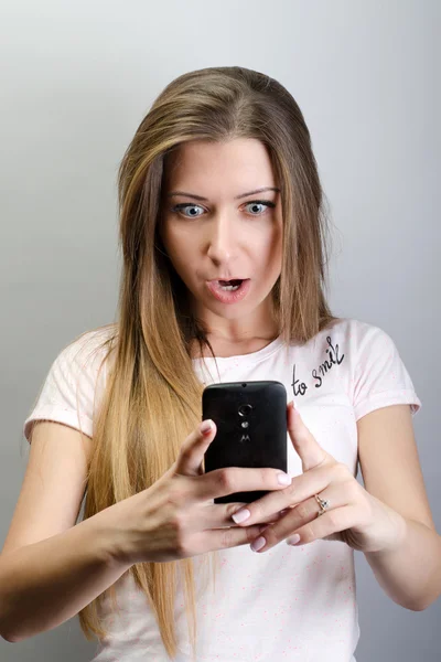 Closeup portrait anxious young girl looking at phone seeing bad news or photos with disgusting emotion on her face isolated outside city background. Human emotion, reaction, expression