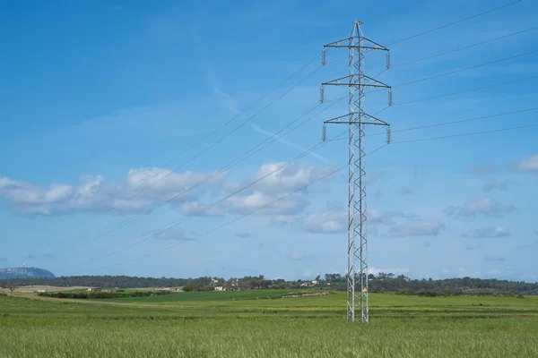 High voltage transmission tower and cable line in the countryside under a blue sky