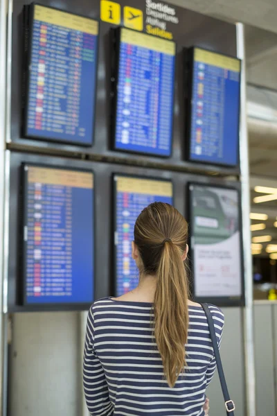 Young girl watching flight information board in airport terminal