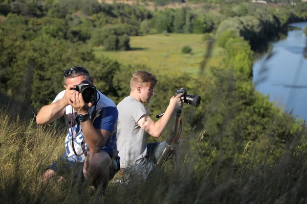 Vinnitsa, Ukraine  - July 18, 2015. Canon 1Ds Mark III & Canon 5D Mark II.  Photographers father and son take off in nature. The father teaches his son the right to use the camera. The meeting of two friends