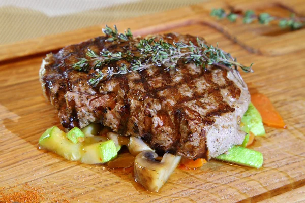 Delicious steak. Beef steak on wooden plate plate. Beef steak medium rare on vegetable cushion  - Stock Image