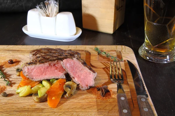 Delicious steak. Beef steak medium rare on vegetable cushion. Beef steak on wooden plate plate - Stock Image