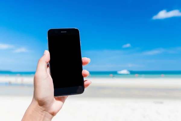 Beautiful woman\'s hand using smart phone at beach. Smartphone black screen.