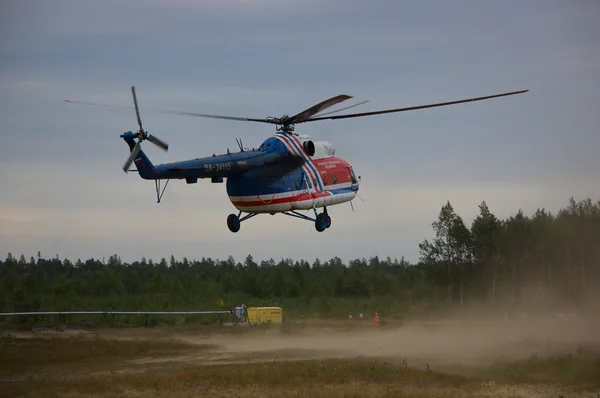 Helicopter Mi-8 landing in cloud of dust on rural airfield.