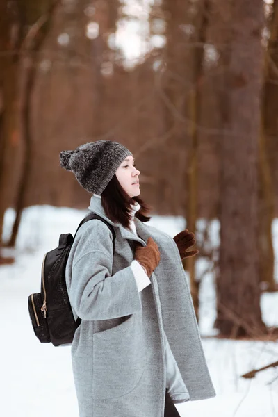 Portrait of a happy beautiful girl with brown hair in the winter forest dressed in a hipster style, lifestyle