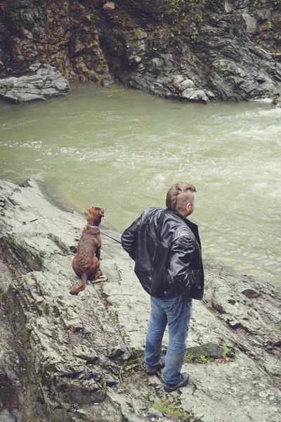 Happy young traveller man with dog hiking traveling in the forest on a sunny day