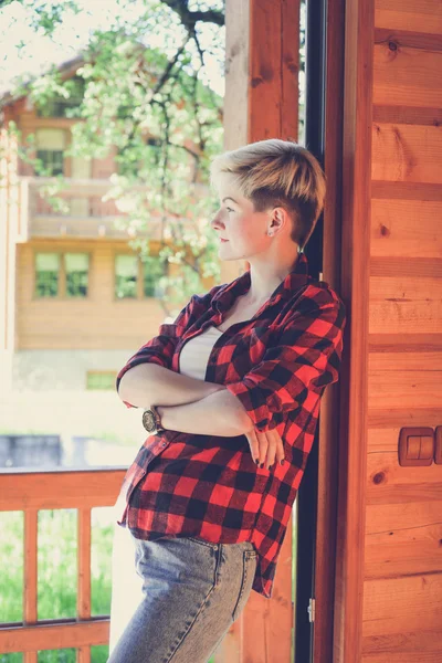 Young blonde woman in red lumberjack shirt, jeans and sneakers