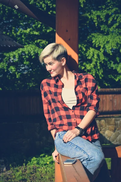 Young blonde woman in red lumberjack shirt, jeans and sneakers