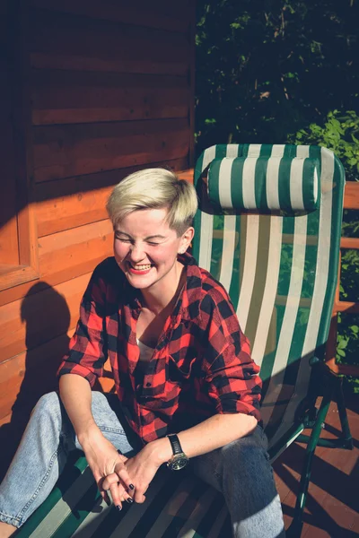 Young blonde woman in red lumberjack shirt, jeans and sneakers