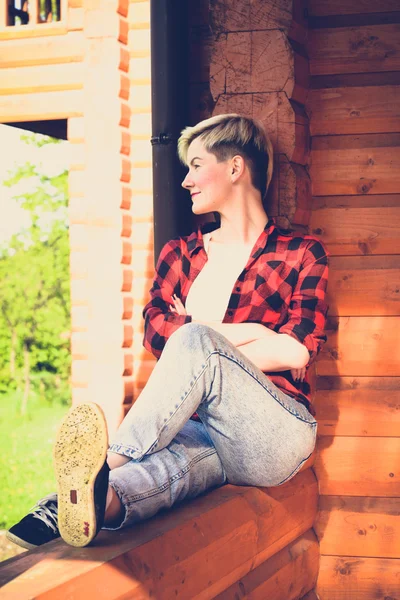 Young blonde woman in red lumberjack shirt, jeans and sneakers