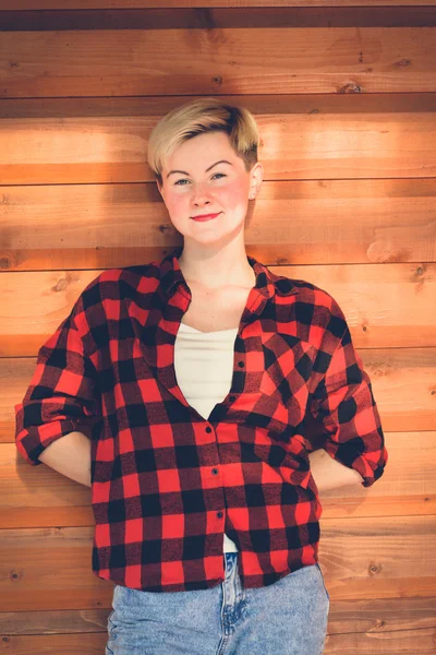 Young blonde woman in red lumberjack shirt, jeans and sneakers