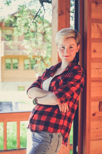 Young blonde woman in red lumberjack shirt, jeans and sneakers