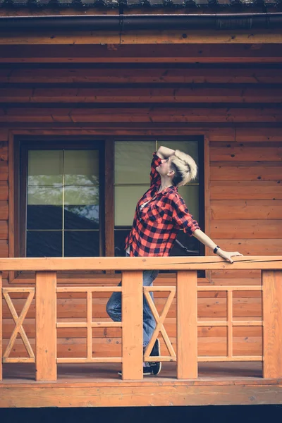 Young blonde woman in red lumberjack shirt, jeans and sneakers