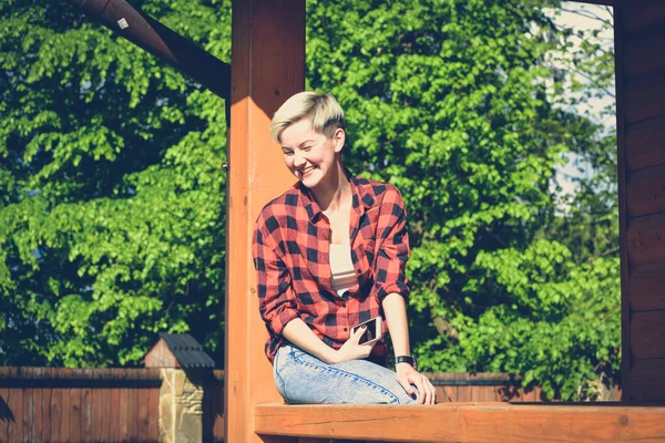 Young blonde woman in red lumberjack shirt, jeans and sneakers