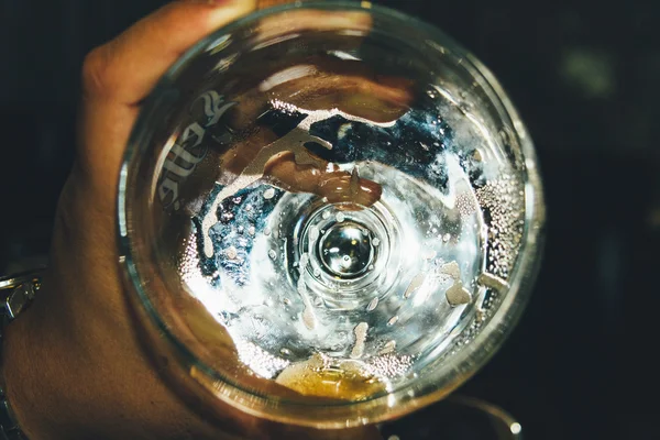 Drunk glass of beer in a hand. Bottom of drunk glass of beer