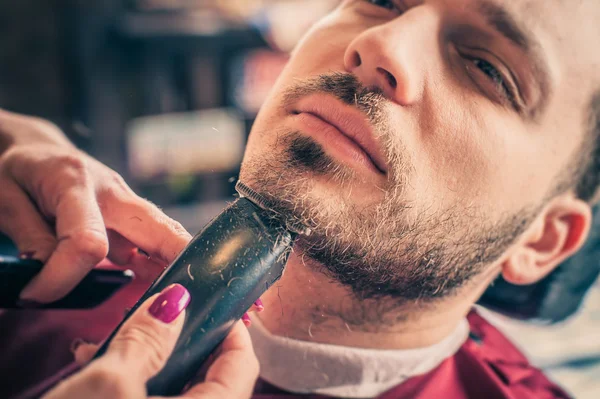 Barber shaving a client with trimmer