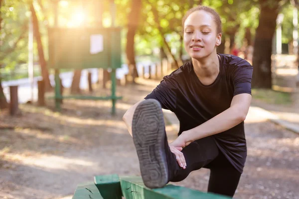 Training outdoors. Fit young woman stretching her legs.