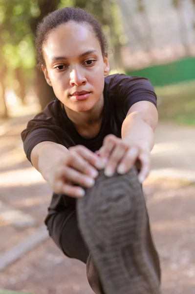 Training outdoors. Fit young woman stretching her legs.