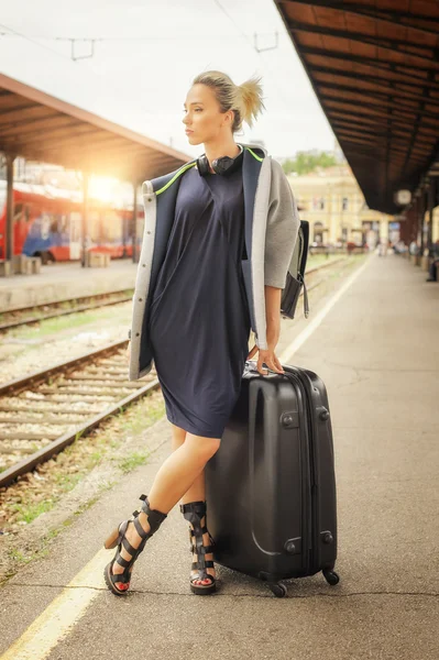 Elegant woman with suitcase posing on the railway station