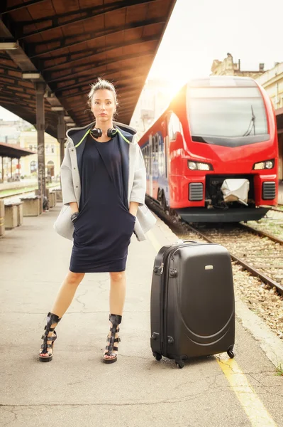 Elegant woman with suitcase posing on the railway station