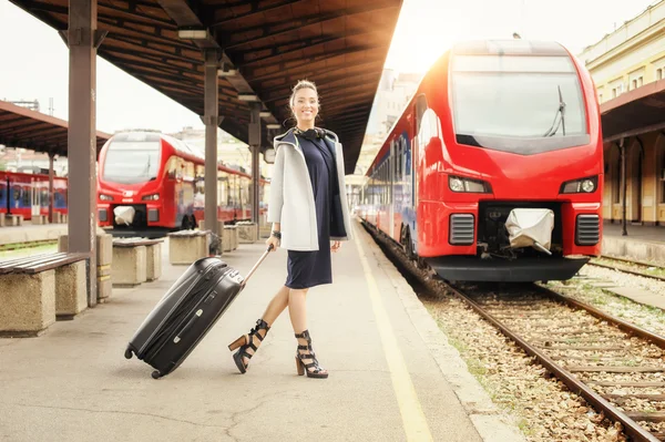 Elegant woman with suitcase posing on the railway station