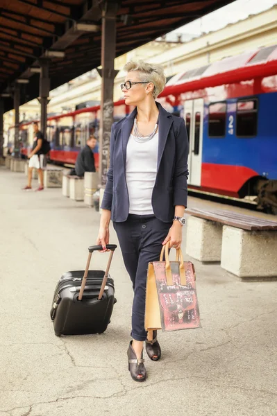 Elegant woman with suitcase posing on the railway station