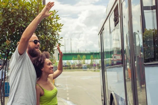 Young couple waving goodbye to their friends on the bus