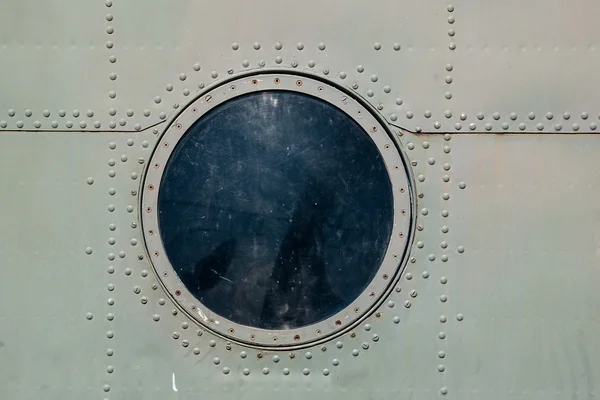 Hatch window of the old aircraft riveted iron plates