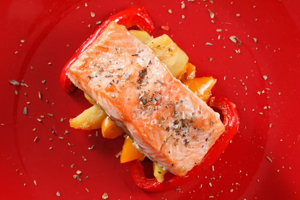 Grilled salmon fillet with vegetables, spices and arugula on a plate