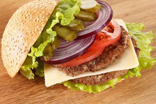 Traditional American cheeseburger. Meat, bun and vegetables close up